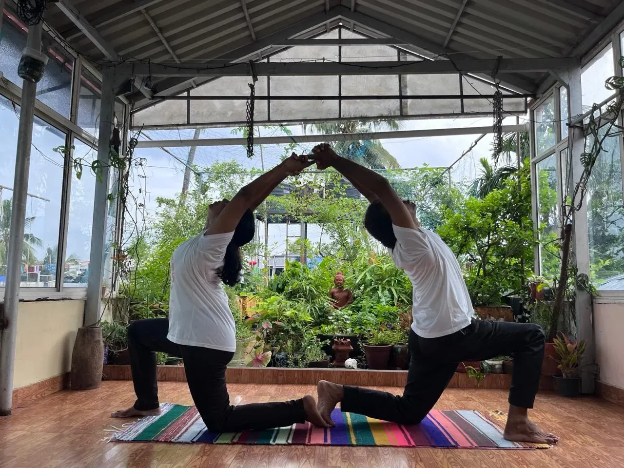 Partner low lunge on a yoga mat in the plant-filled studio, 100-hour yoga teacher training