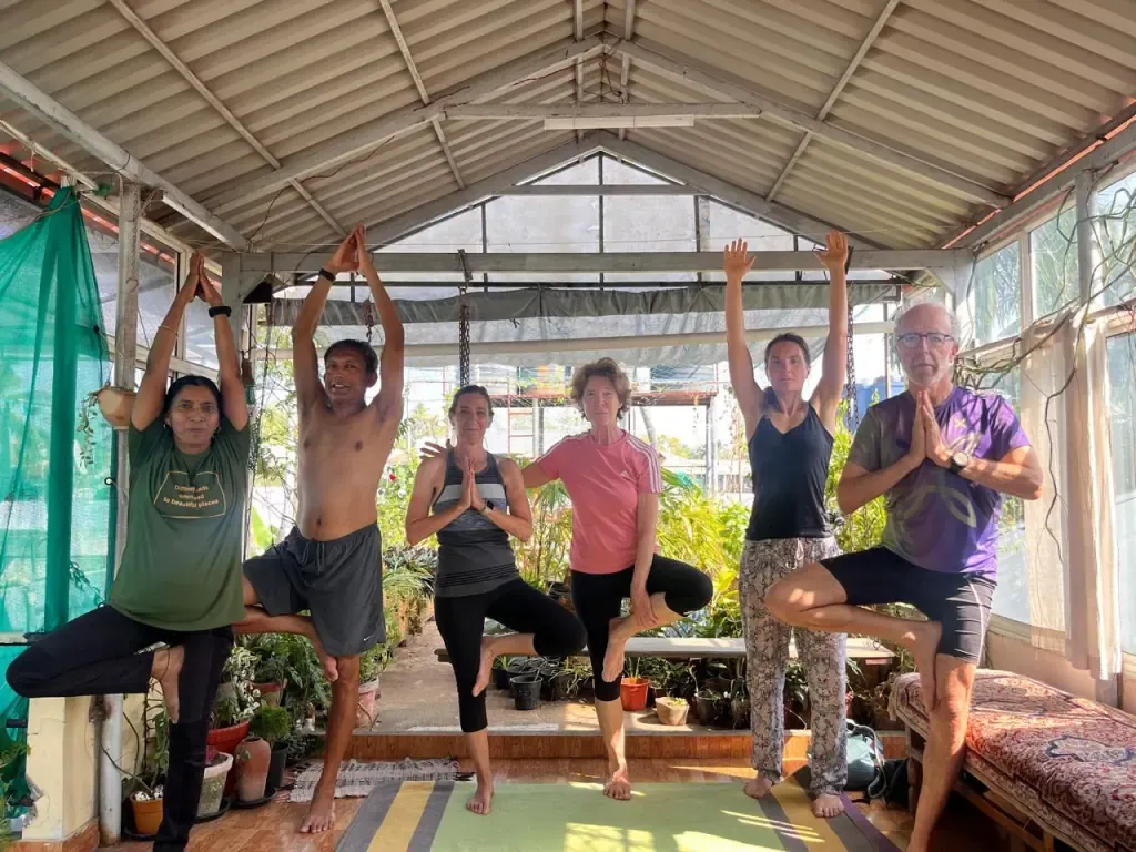 Guests and teachers balancing in tree pose together in the shala