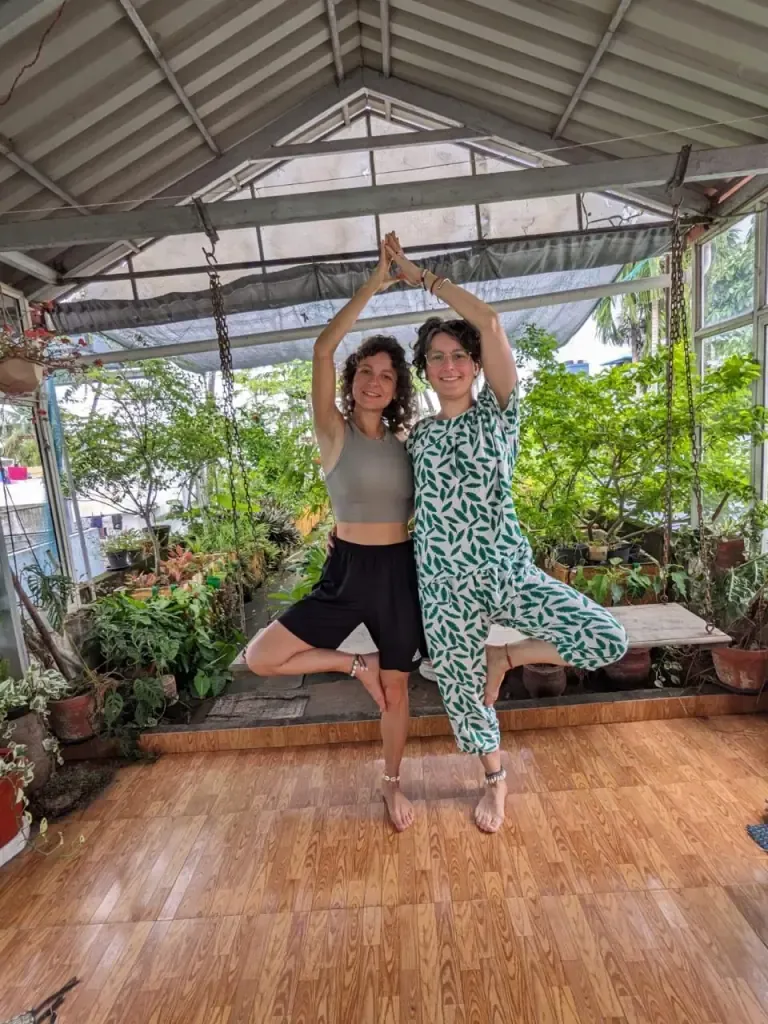 Two guests in partner tree pose with their arms joined overhead