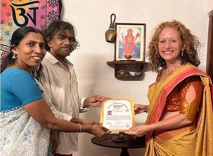 Anitha and Ramesh presenting a yoga and Ayurveda course certificate to a graduate