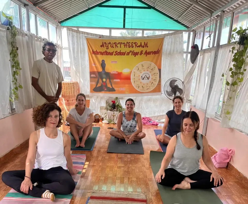 Guests seated on yoga mats with their teacher beneath the Ayurtheeram banner